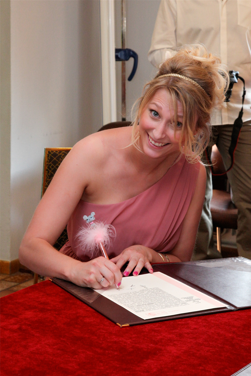 Lors d'un mariage, le témoin, une femme, affiche un large sourire.