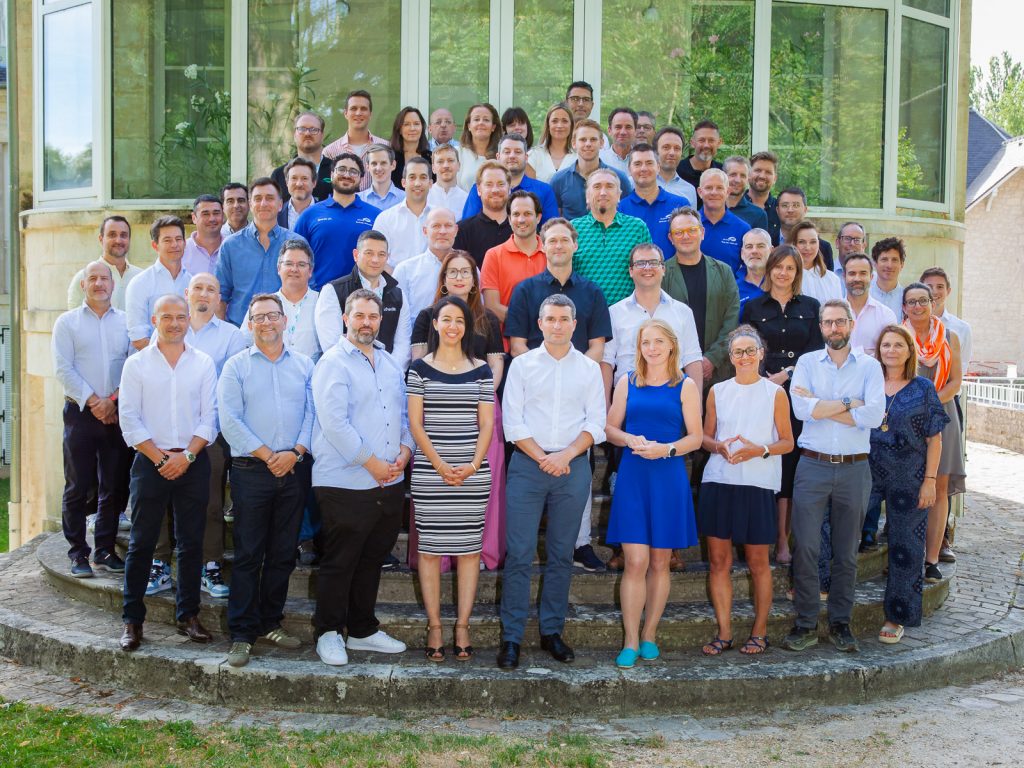 Photo de groupe des collaborateurs et de la direction de l'entreprise iDVERDE, réunis en extérieur sur des marches en pierre lors d'un reportage réalisé par un photographe corporate à Chantilly.