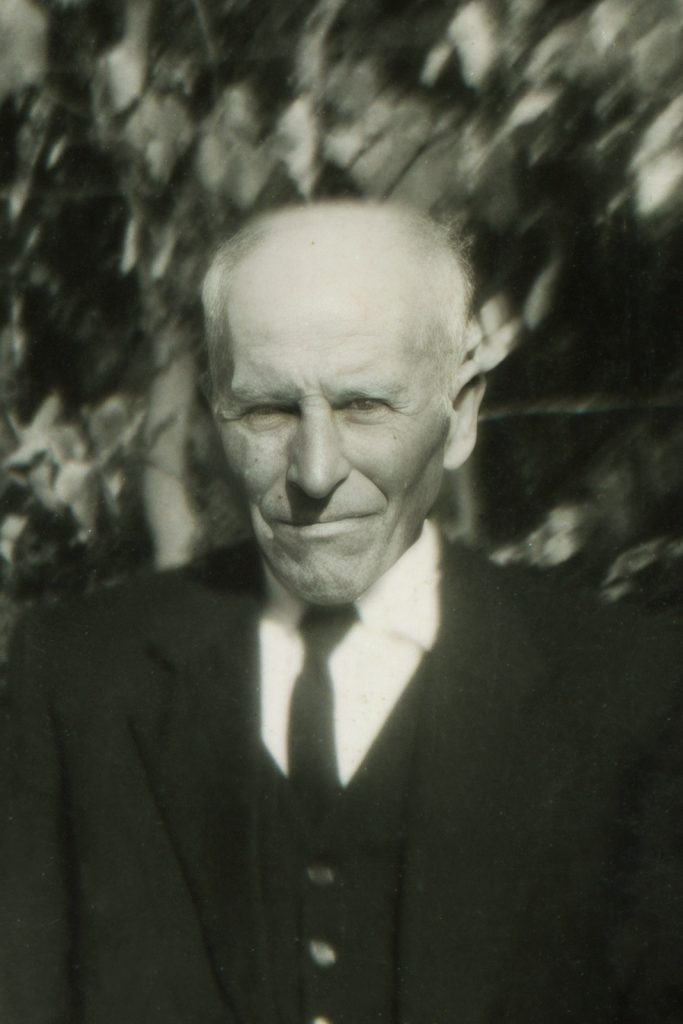 Photo argentique en noir et blanc. Portrait d'un homme âgé portant une veste de costume sombre avec une cravate.